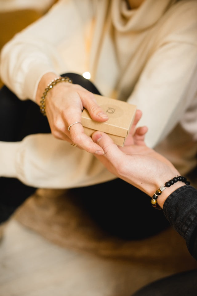 Person lächelt glücklich, während sie ein Geschenk mit edlem Jade Schmuck auspackt – ein Symbol für Eleganz und positive Energie.