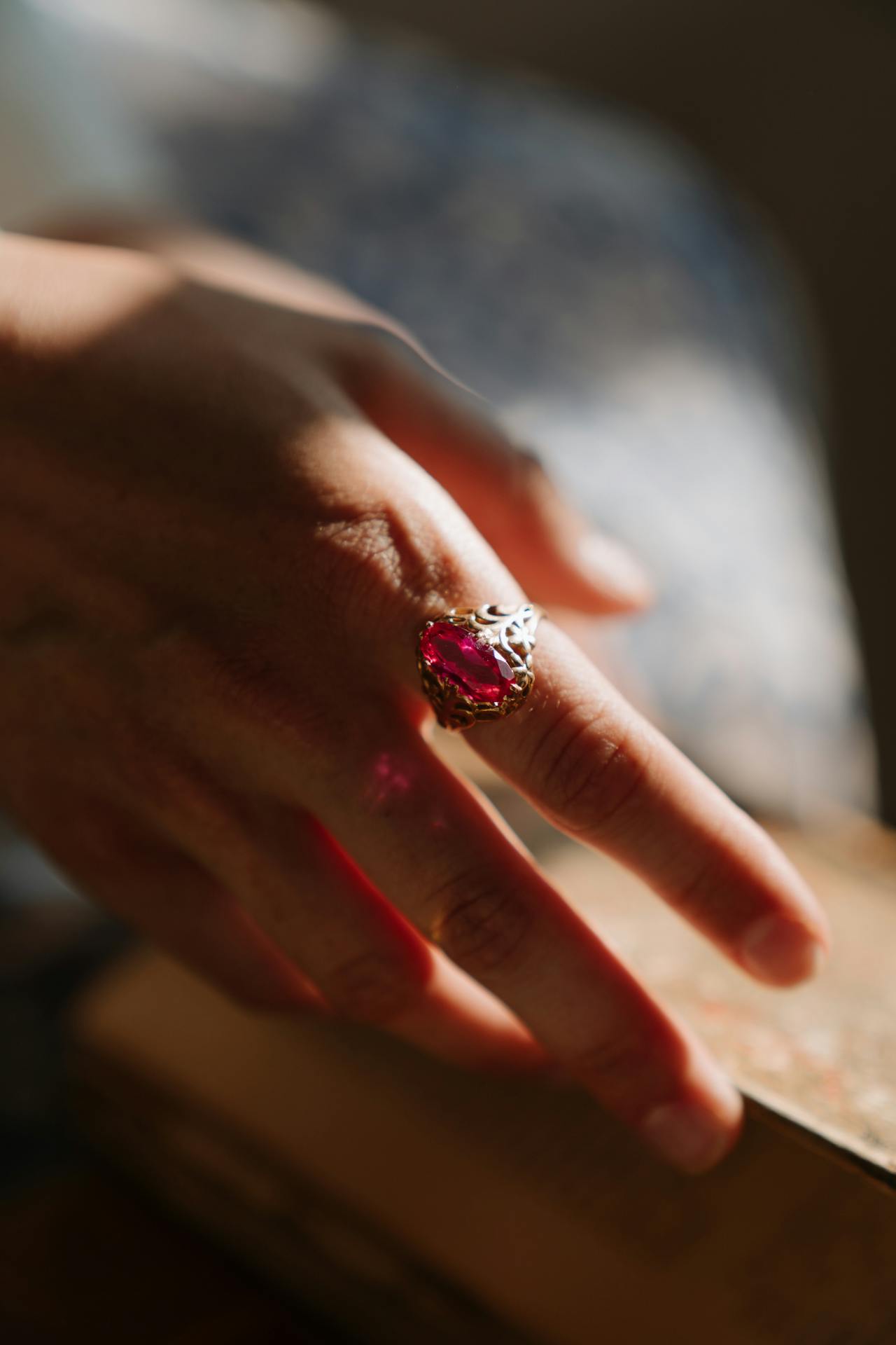 Stilvoller Rubin Schmuck Ring an einer Hand, eingefangen in natürlichem Licht, das die rote Brillanz des Edelsteins betont.